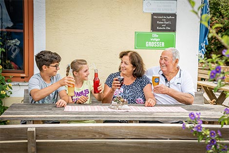 Oma, Opa und die zwei Enkelkinder auf der Terrasse und haben jeweil ein Getränk in der Hand.
