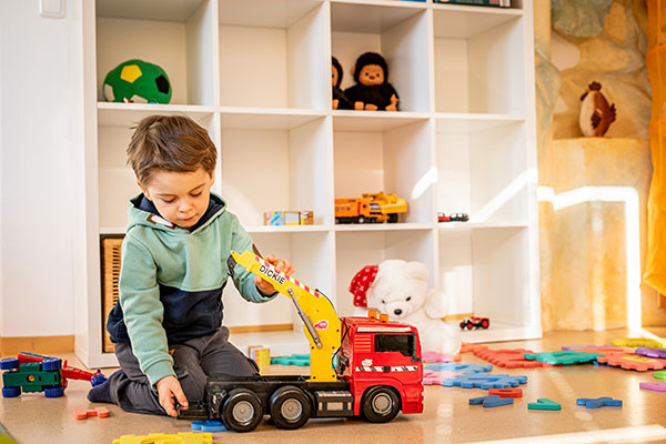 Bub spielt gerade im Spielzimmer mit einem LKW.