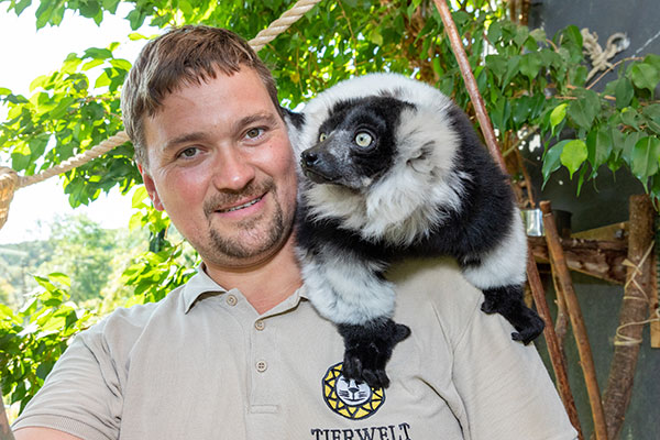 Tierpfleger mit Tier auf Schulter.
