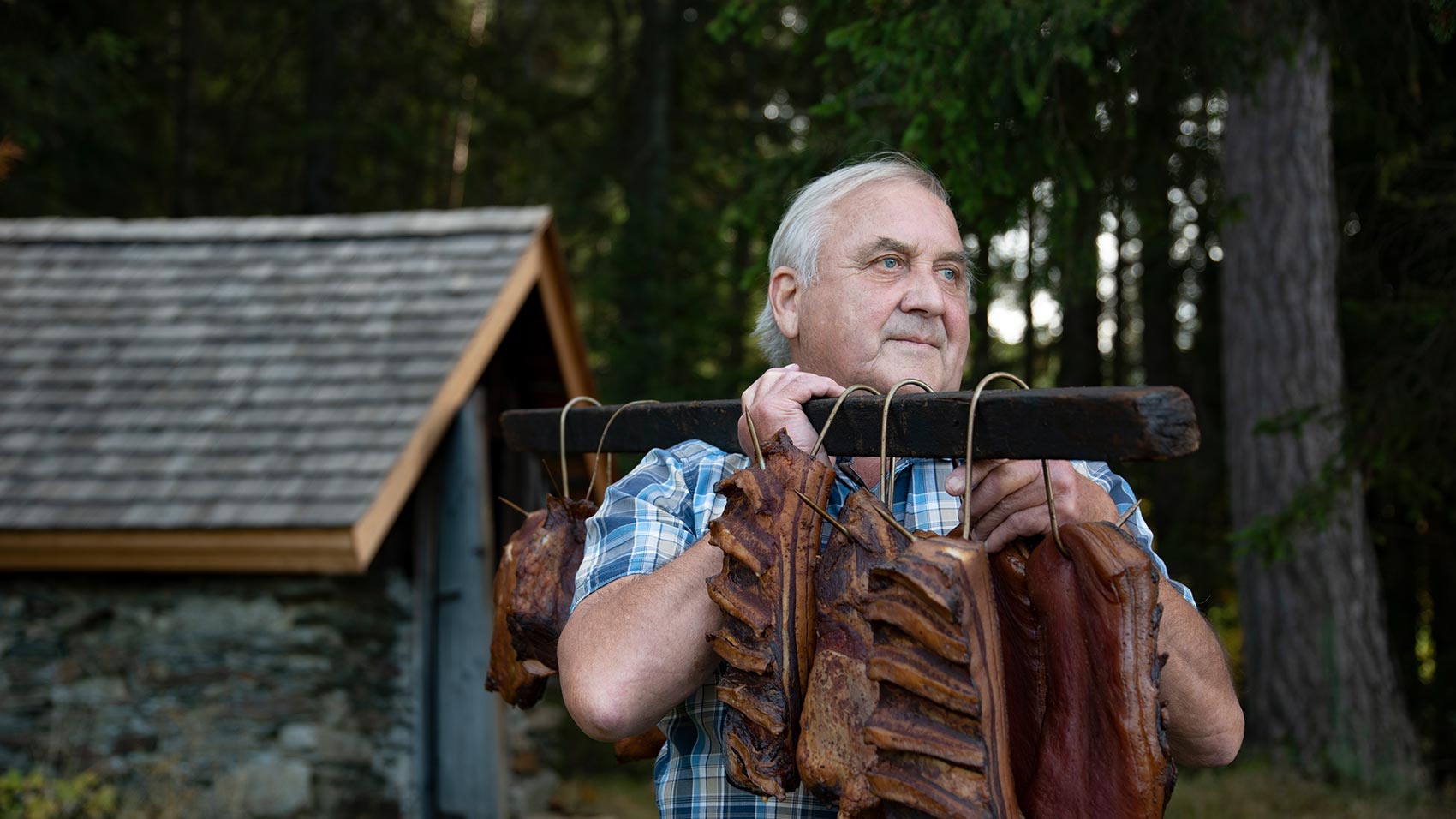 Opa Orthofer trägt das Oster-Fleisch mit einem Holzbalken über der Schulter  vom Selchhaus Richtung Gasthaus