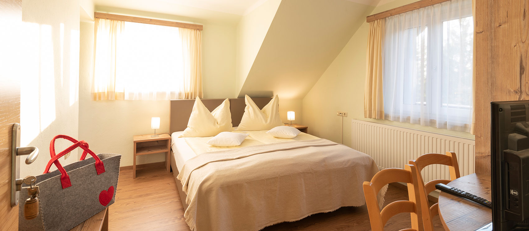 Blick in ein Doppelzimmer mit - Fenster udn Doppelbett sichtbar.