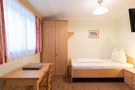 Das Einzelzimmer im Gasthof Orthofer - ausgestattet mit Kasten, Einzelbett, Tisch und Stuhl.