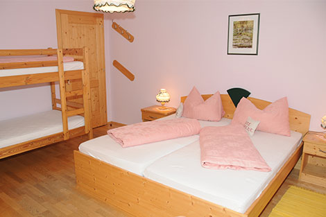 Blick in das Familienzimmer: Ein Doppelbett und ein Stockbett aus Naturholz.