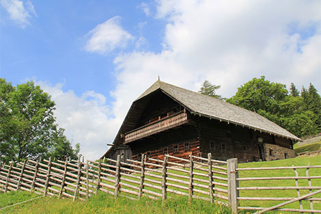 Blick auf das Geburtshaus von Peter Rosegger - im Vordergrund ein Jägerzaun und im Hintergrund der Bauernhof